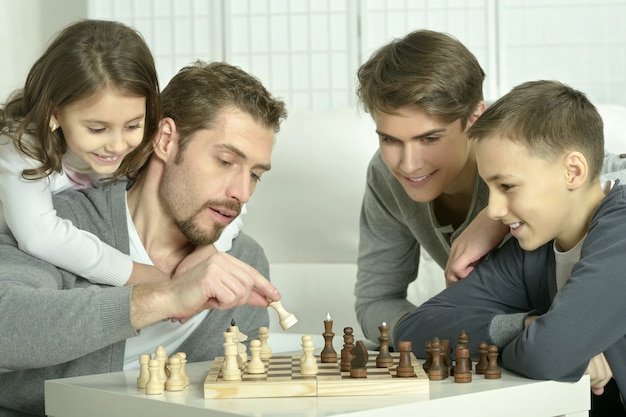 Familia jugando al ajedrez en una mesa en casa