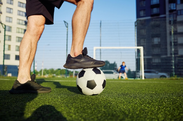 La familia jugando al fútbol en el campo se centra en el padre pie en la pelota