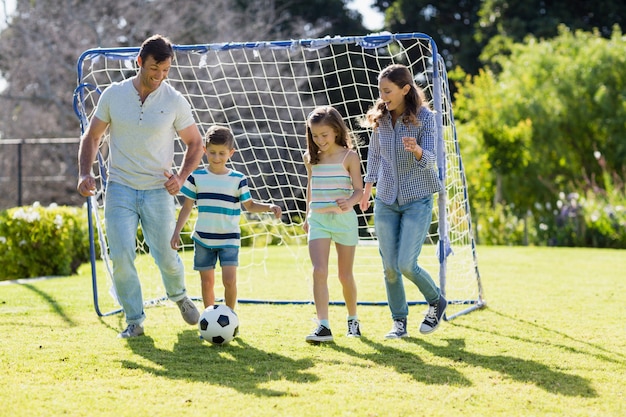 Familia jugando al fútbol juntos en el parque