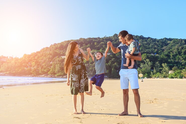 Familia jugando con el hijo en la playa a la hora de la puesta del sol