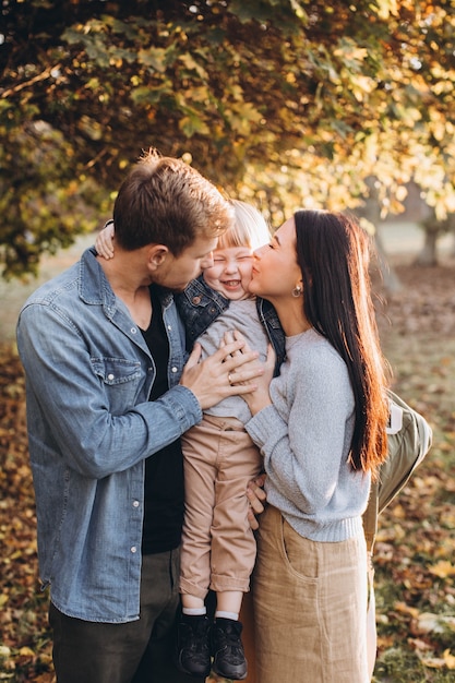 Familia jugando en el parque de otoño divirtiéndose