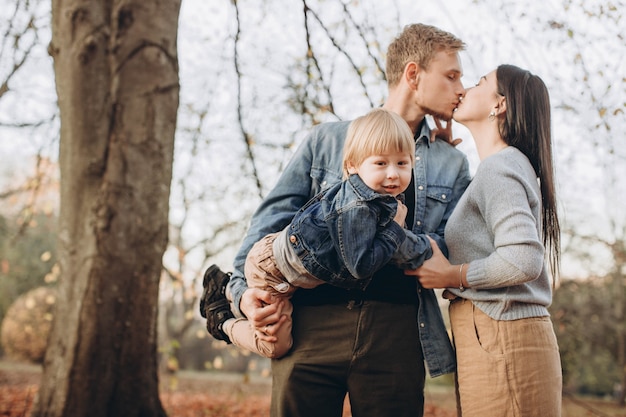 Familia jugando en el parque de otoño divirtiéndose