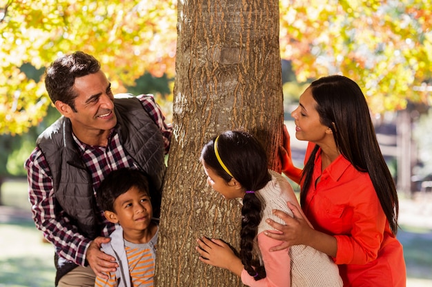 Familia juguetona de pie junto al árbol