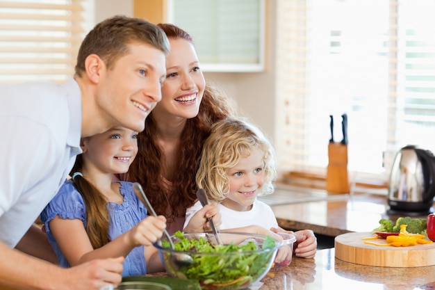 Família juntamente com salada na cozinha