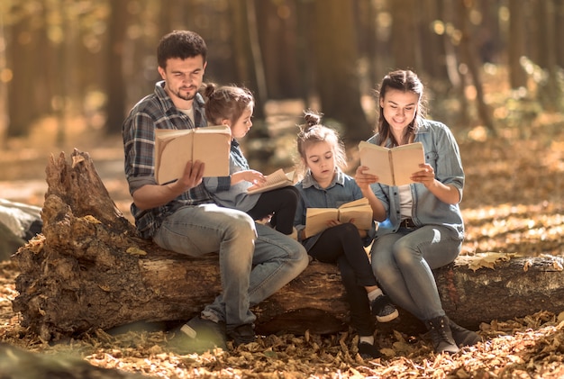 Família junto lendo livros na floresta.