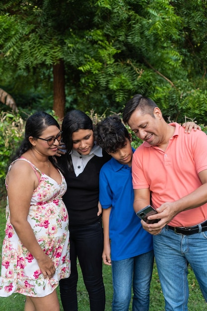 Familia latina con dos adolescentes usa celular para hacer videollamada