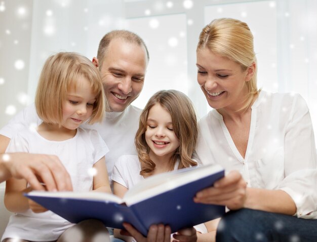 família, lazer, educação e pessoas - sorrindo mãe, pai e meninas lendo livro sobre fundo de flocos de neve