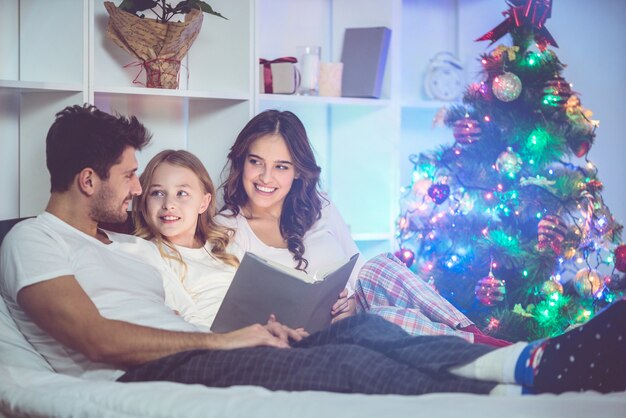 La familia leyó el libro cerca del árbol de Navidad. tiempo de la tarde