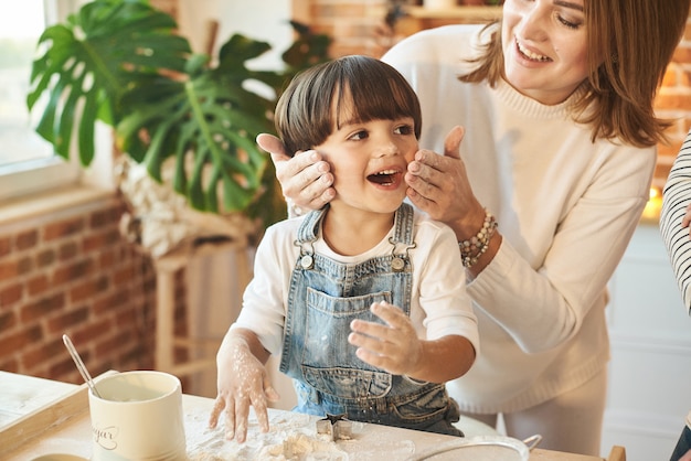 Família linda jovem se divertindo e cozinhando na cozinha ensolarada