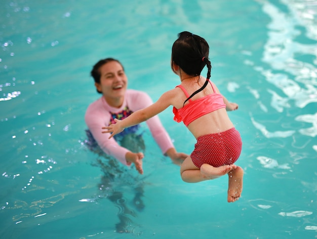 Familia de madre enseñando a niños en la piscina