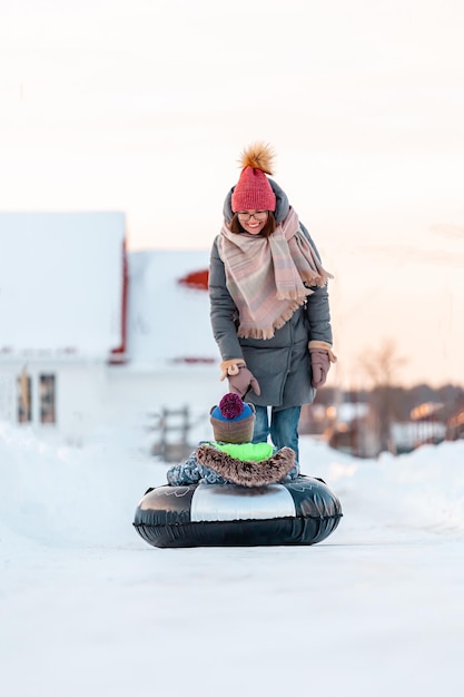 Família, mãe e filho, atividades de inverno juntas em tubos de neve na estrada de neve de inverno