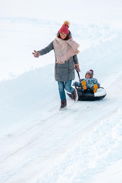 Família, mãe e filho, atividades de inverno juntas em tubos de neve