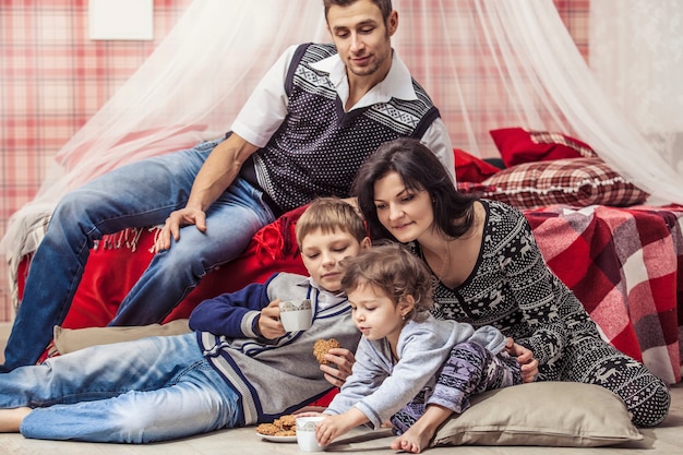 Família, mãe e pai, filhos no quarto em casa no interior vermelho de Natal