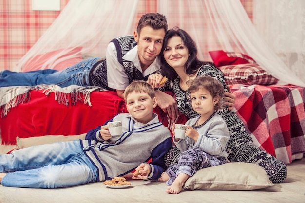 Família, mãe e pai, filhos no quarto em casa no interior vermelho de natal