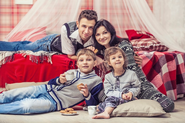 Família, mãe e pai, filhos no quarto em casa no interior vermelho de Natal