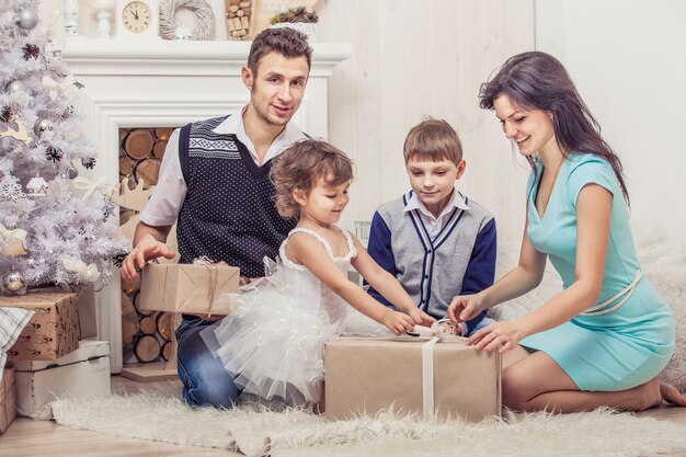Família, mãe, pai e filhos com presentes em lindas caixas no interior de Natal