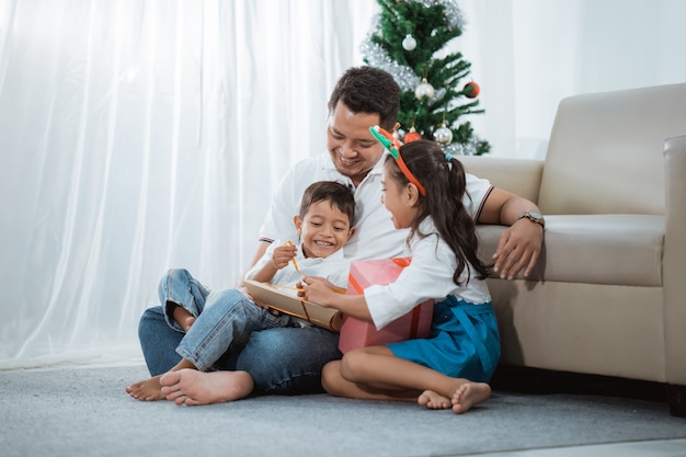 Familia malaya abriendo sus regalos de Navidad juntos en casa