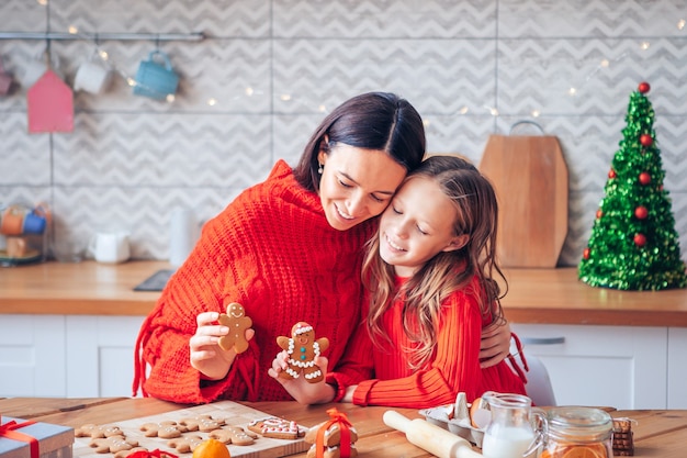 Foto familia de mamá e hija con galletas de navidad en la cocina