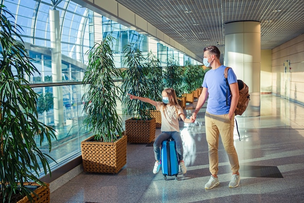 Familia en mascarilla en el aeropuerto. Padre e hijo usan mascarilla durante el brote de coronavirus y gripe. Protección contra Coronavirus y gripp