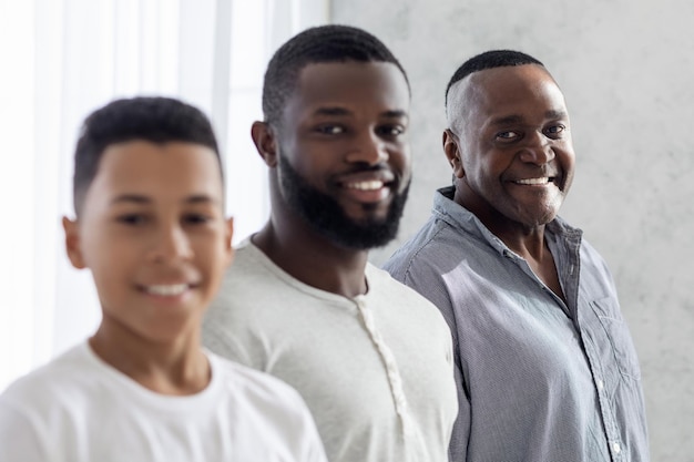 Família masculina multigeracional. Retrato de filho negro sorridente, pai e avô em fila e olhando para a câmera, closeup