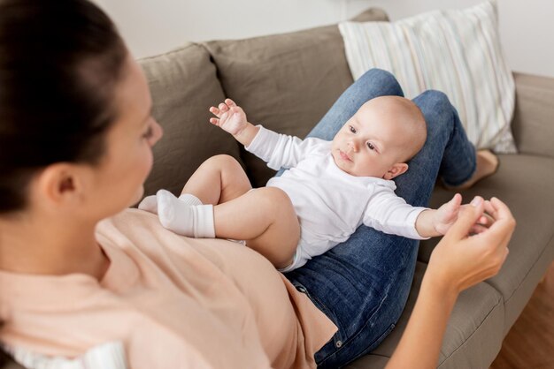 família, maternidade e conceito de pessoas mãe feliz com um menino deitado no sofá em casa