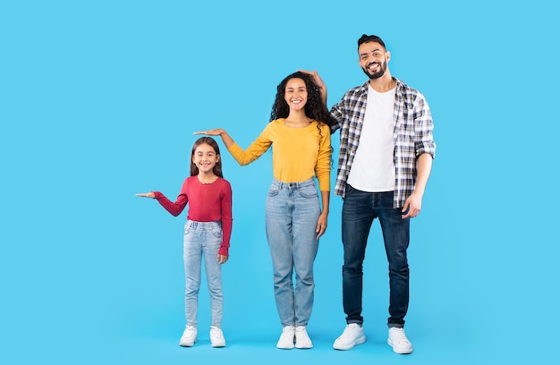 Familia del medio oriente que muestra el fondo azul de la altura de los demás