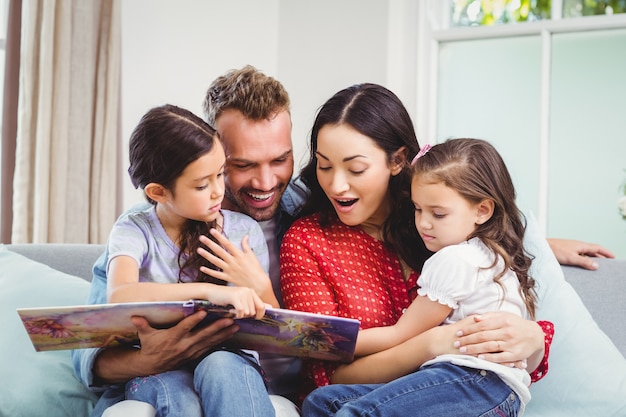 Familia mirando en el libro de imágenes mientras está sentado en el sofá