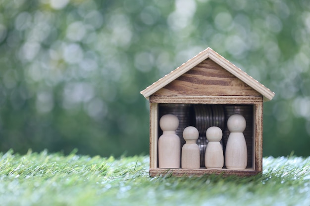 Familia modelo en casa modelo y pila de monedas dinero sobre fondo verde natural, ahorre dinero para prepararse en el futuro y el concepto de finanzas familiares