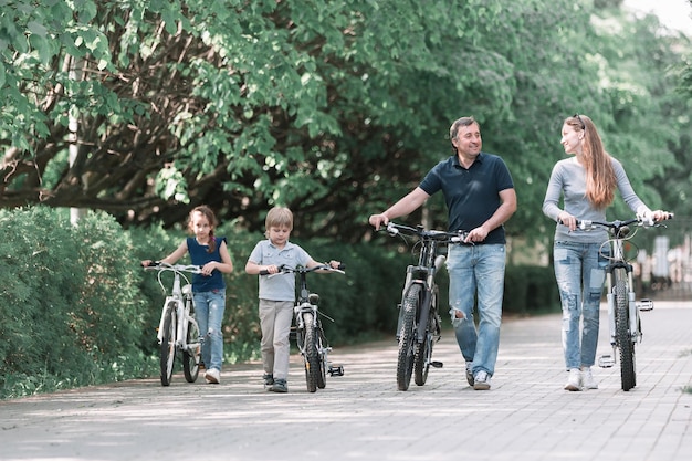 Família moderna com suas bicicletas andando pelo parque da cidade