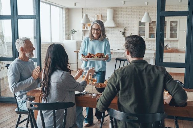 Família moderna de várias gerações sorrindo enquanto jantam juntos