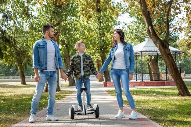 Família moderna, pai mãe filho monta um hoverboard no parque