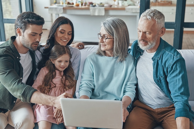 Família moderna passando um tempo junta e sorrindo enquanto está sentada no sofá em casa