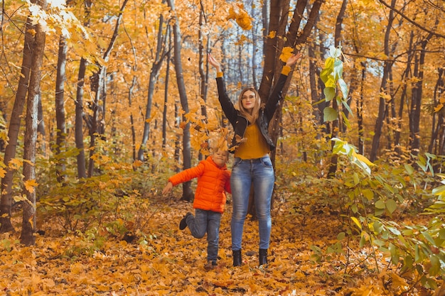 Família monoparental brincando com folhas de outono no parque feliz mãe e filho jogando folhas de outono