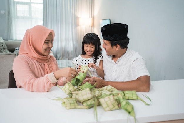 Família muçulmana asiática feliz fazendo ketupat em casa antes do eid mubarak