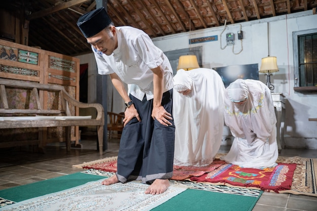 Família muçulmana asiática rezando jamaah junta em casa