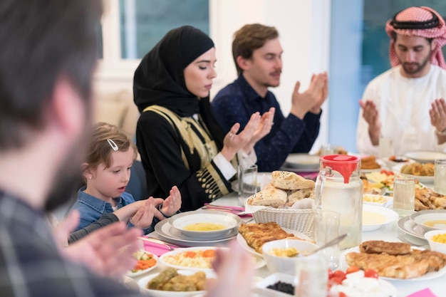 Família muçulmana fazendo iftar dua para quebrar o jejum durante o Ramadã.