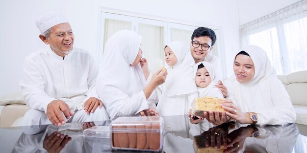 Família muçulmana feliz de três gerações come biscoitos