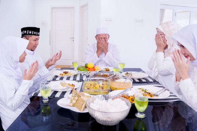 Família muçulmana rezando juntos antes do jantar