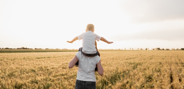 Família muito feliz de mãe e filho se divertindo ao ar livre ao pôr do sol de verão