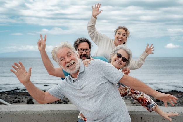 Família multi-geração brincalhona se divertindo juntos em uma excursão ao ar livre à beira-mar gesticulando