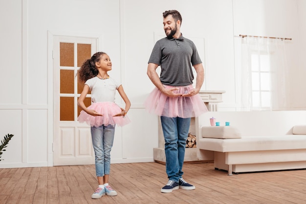 familia multicultural en faldas de tul rosa tutu bailando en casa