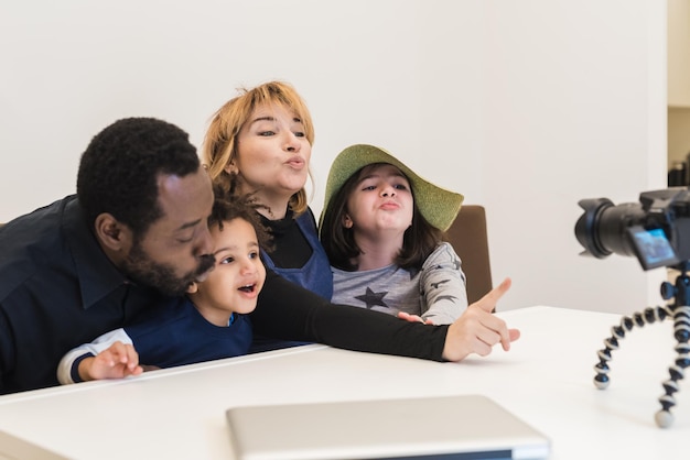 Familia multiétnica, padre negro y madre blanca con dos hijos mestizos, envían besos a sus familiares en una videollamada, familia de vloggers multirraciales besa virtualmente a sus seguidores