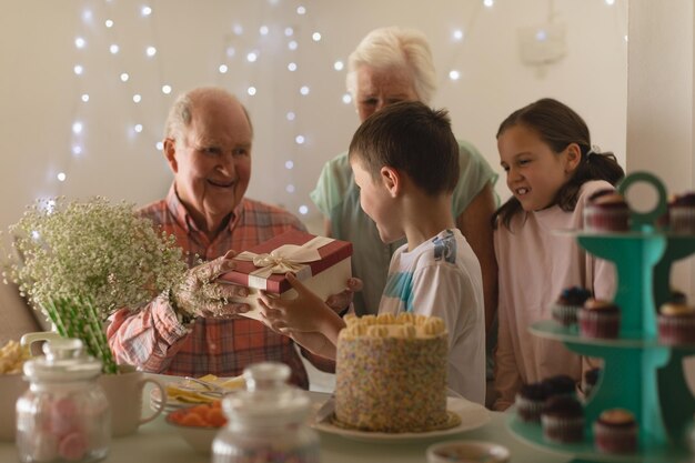 Familia multigeneracional dando un regalo al niño de cumpleaños