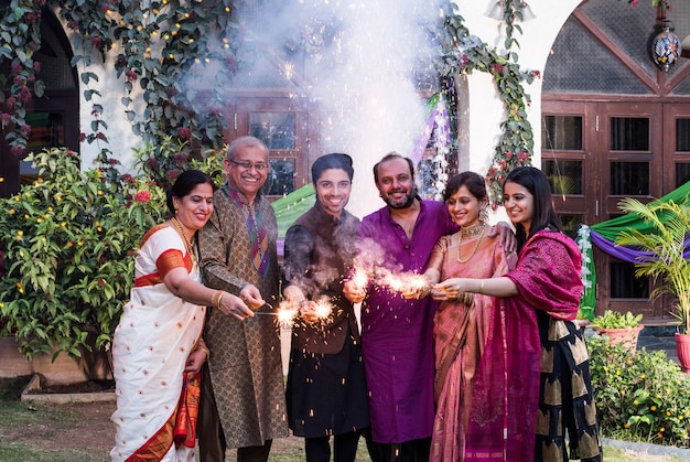 Familia multigeneracional india celebrando el festival de Diwali jugando con petardos fuera de casa