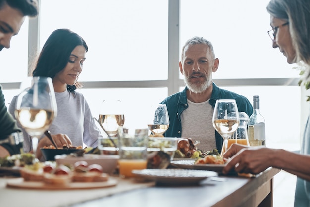 Familia multigeneracional moderna comunicándose mientras cenan juntos