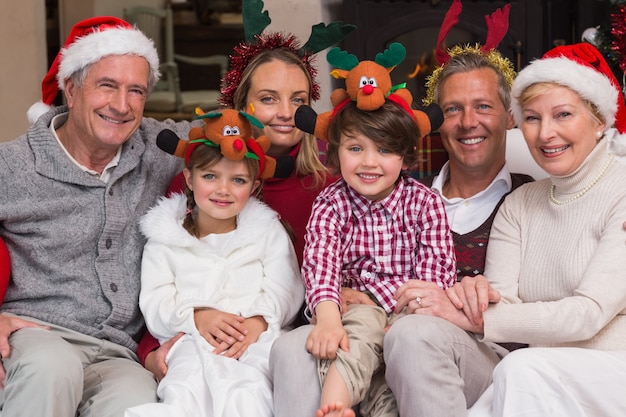 Familia multigeneracional con sombreros de santa en el sofá