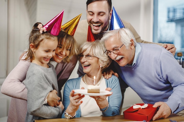 Família multigeracional alegre se divertindo enquanto comemora o aniversário da mulher sênior em casa