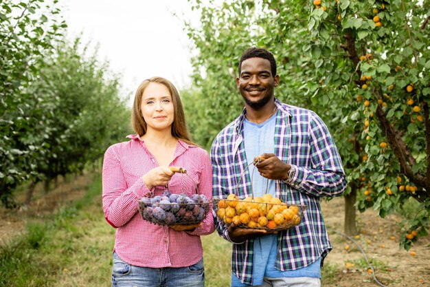 Família multirracial feliz em seu jardim de frutas