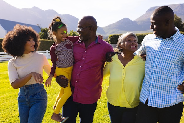 Familia multirracial multigeneracional divirtiéndose y disfrutando de un paseo juntos en el patio en un día soleado