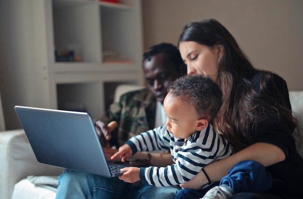 Foto familia multirracial sentada en un sofá con una computadora